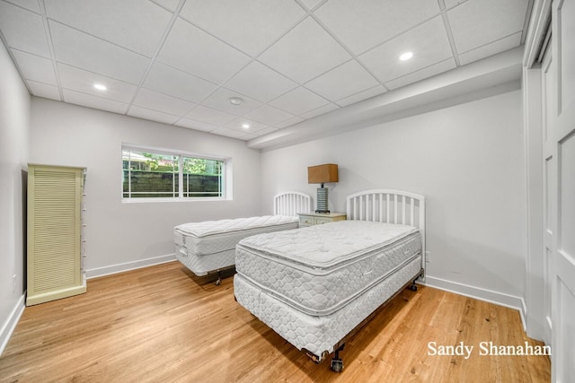 bedroom featuring a drop ceiling and hardwood / wood-style floors