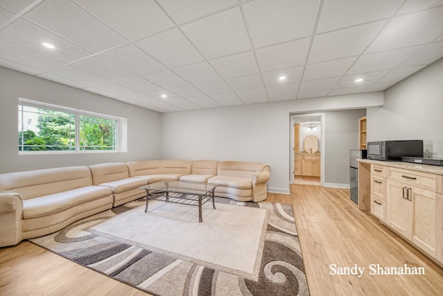 living room with a drop ceiling and light wood-type flooring