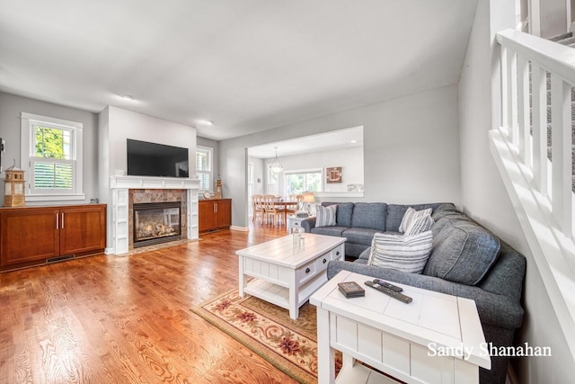 living room with a tiled fireplace and light hardwood / wood-style floors