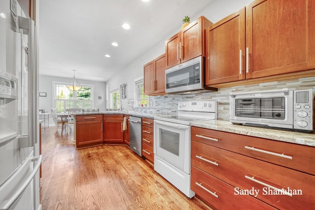 kitchen featuring pendant lighting, light hardwood / wood-style flooring, appliances with stainless steel finishes, backsplash, and light stone counters