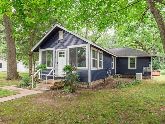 view of front of house with central AC unit and a front yard