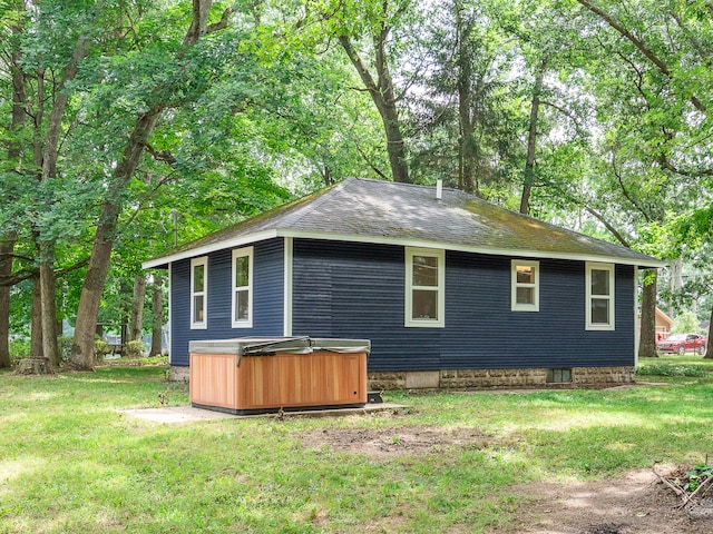 view of home's exterior featuring a yard and a hot tub