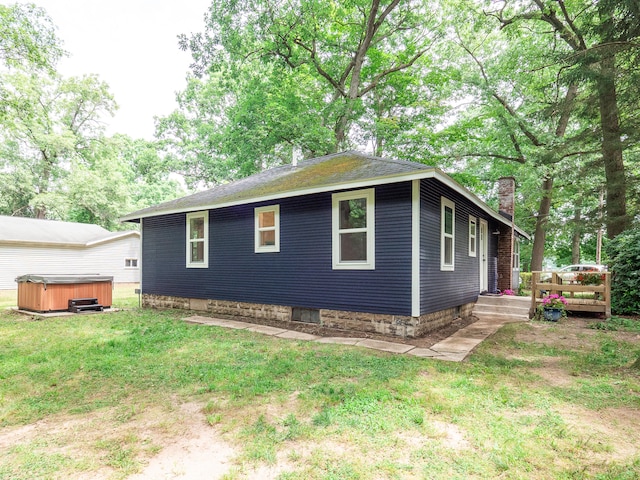 view of home's exterior featuring a yard and a hot tub