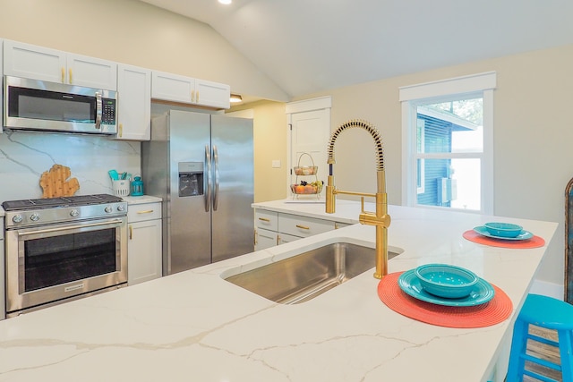 kitchen with stainless steel appliances, decorative backsplash, sink, light stone countertops, and vaulted ceiling