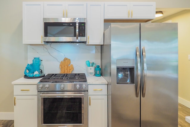 kitchen featuring white cabinets, stainless steel appliances, wood-type flooring, and backsplash