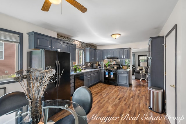 kitchen featuring sink, gray cabinetry, backsplash, black appliances, and dark hardwood / wood-style flooring