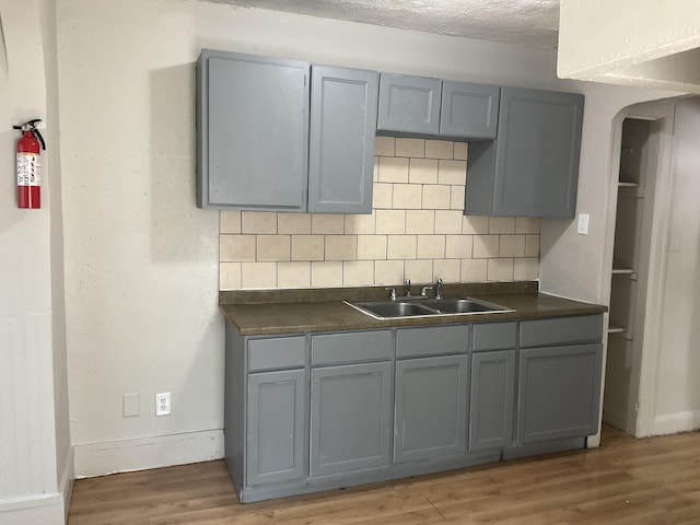 kitchen with gray cabinetry, sink, decorative backsplash, and dark wood-type flooring