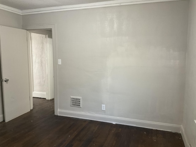 empty room featuring crown molding, dark wood-type flooring, and a textured ceiling