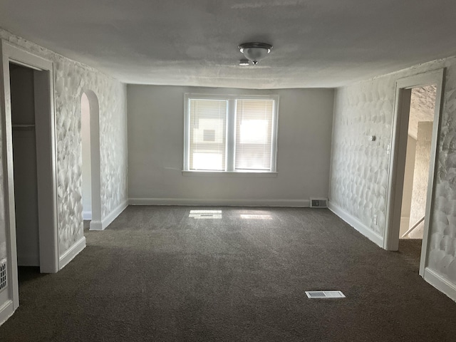 unfurnished room featuring dark colored carpet