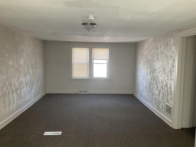 unfurnished room featuring dark colored carpet