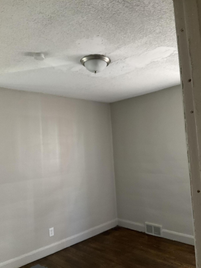 unfurnished room with dark wood-type flooring and a textured ceiling