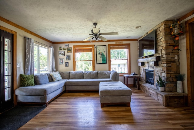 living room with dark hardwood / wood-style flooring, crown molding, a fireplace, and a textured ceiling