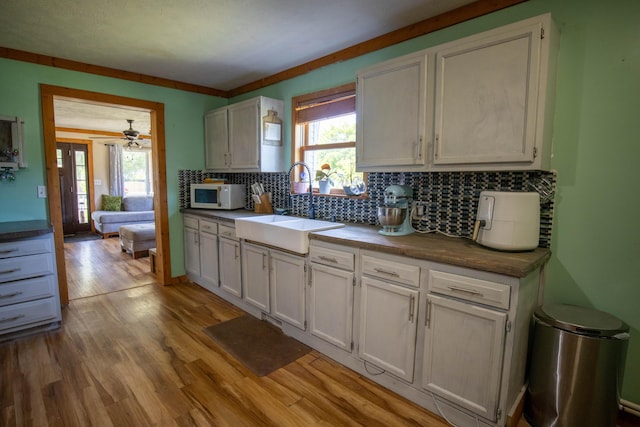 kitchen with white cabinetry, sink, light hardwood / wood-style flooring, and tasteful backsplash