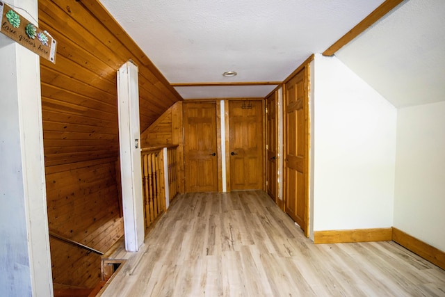 additional living space featuring vaulted ceiling, wooden walls, and light hardwood / wood-style floors