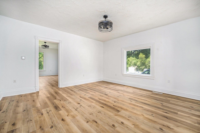 empty room featuring a textured ceiling and light wood-type flooring