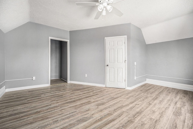 additional living space featuring wood-type flooring, a textured ceiling, vaulted ceiling, and ceiling fan