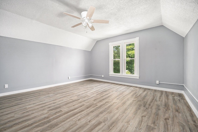 additional living space with lofted ceiling, hardwood / wood-style floors, a textured ceiling, and ceiling fan