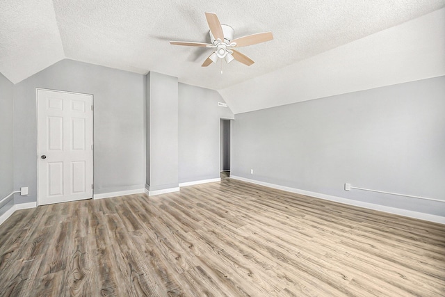 additional living space featuring vaulted ceiling, a textured ceiling, and ceiling fan