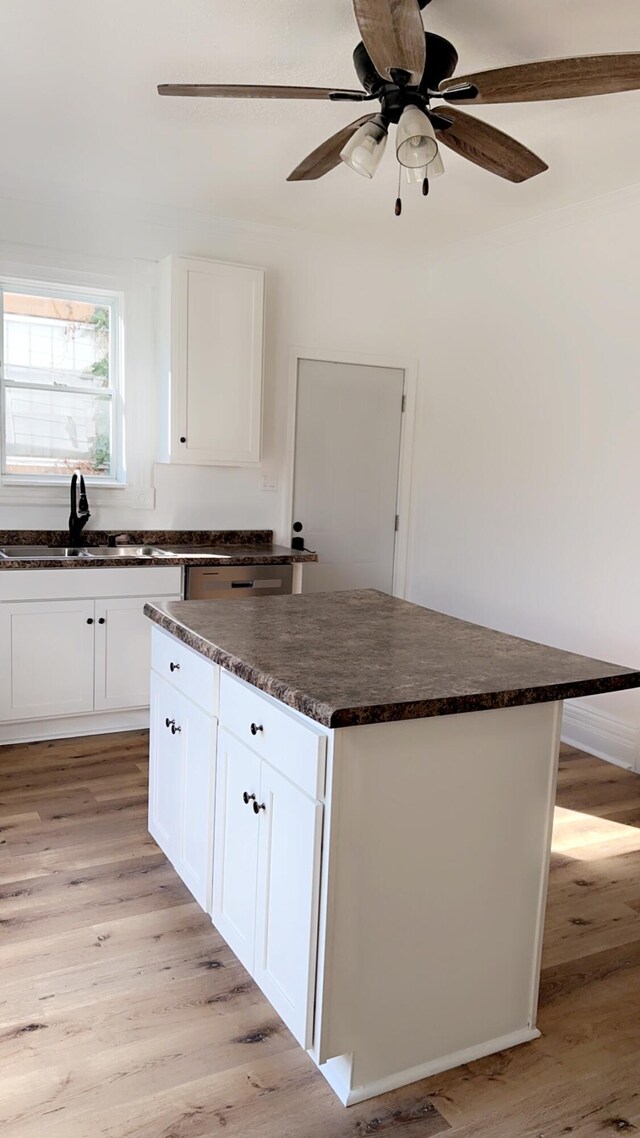 kitchen with light hardwood / wood-style floors, sink, a kitchen island, and white cabinets