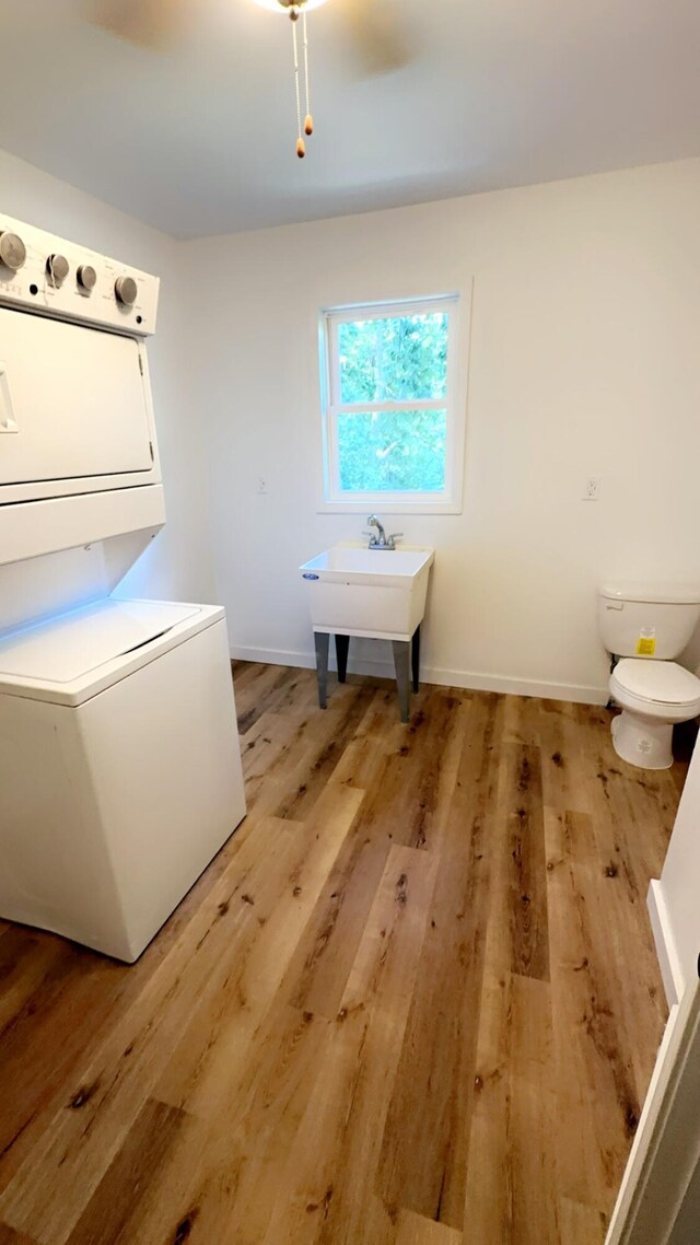 washroom featuring stacked washer and dryer, sink, and light hardwood / wood-style floors