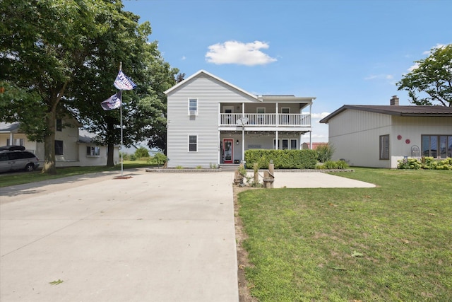 view of property featuring a balcony and a front yard