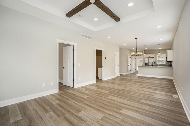 unfurnished living room featuring beamed ceiling, light wood-type flooring, sink, and a chandelier