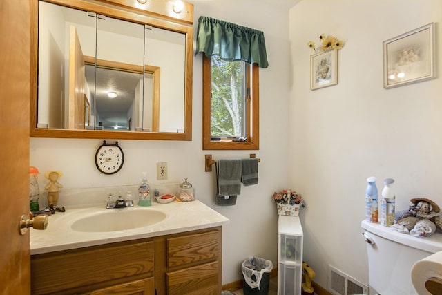half bathroom featuring vanity, toilet, and visible vents