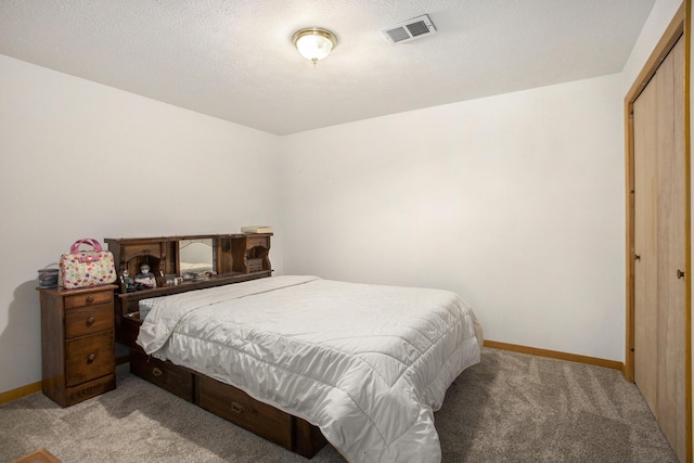 bedroom with visible vents, baseboards, light carpet, a closet, and a textured ceiling