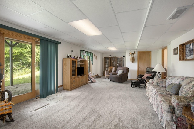 carpeted living area featuring visible vents, baseboards, and a drop ceiling