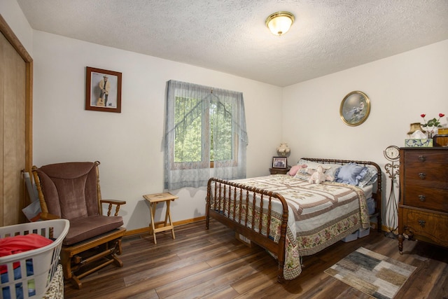 bedroom with baseboards, a textured ceiling, and wood finished floors