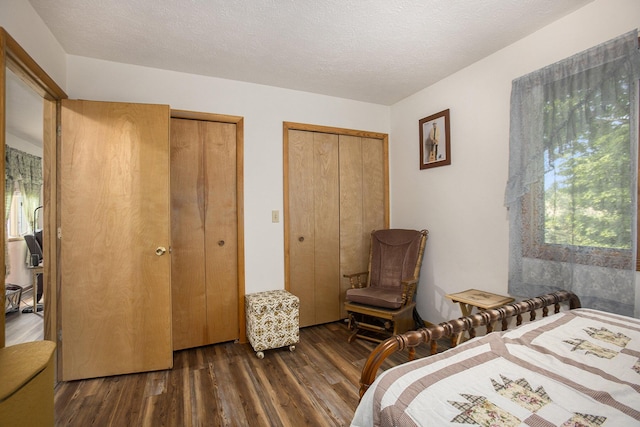 bedroom with two closets, wood finished floors, and a textured ceiling