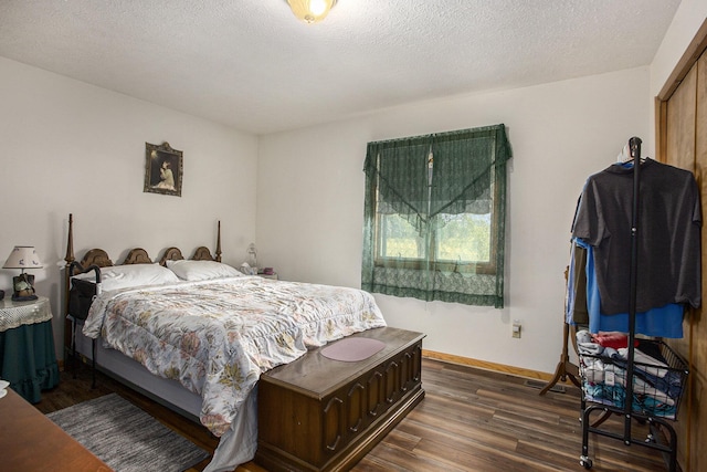bedroom with dark wood-style floors, a textured ceiling, and baseboards