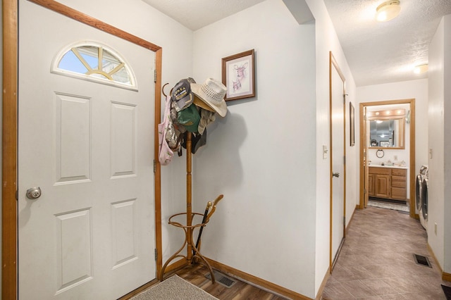 foyer entrance with visible vents, baseboards, and a textured ceiling