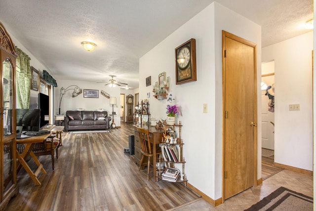 living room with baseboards, a textured ceiling, ceiling fan, and wood finished floors