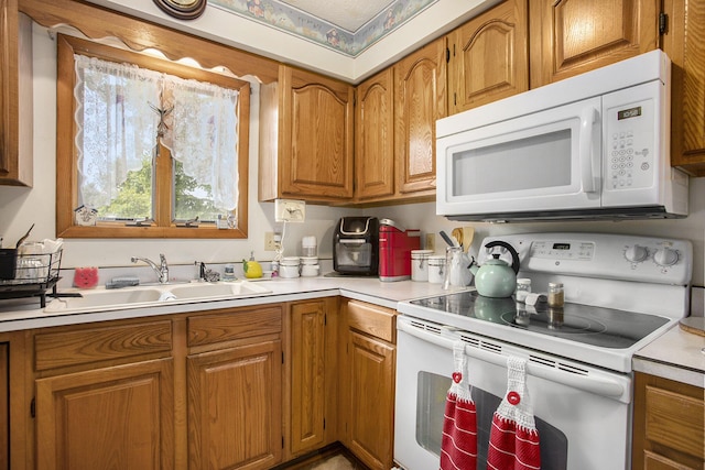 kitchen with white appliances, light countertops, brown cabinets, and a sink