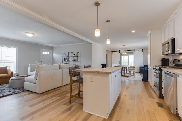 kitchen with a breakfast bar area, a center island, pendant lighting, stainless steel appliances, and white cabinets