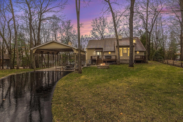 back of property at dusk with a gazebo, a deck, a carport, and a yard