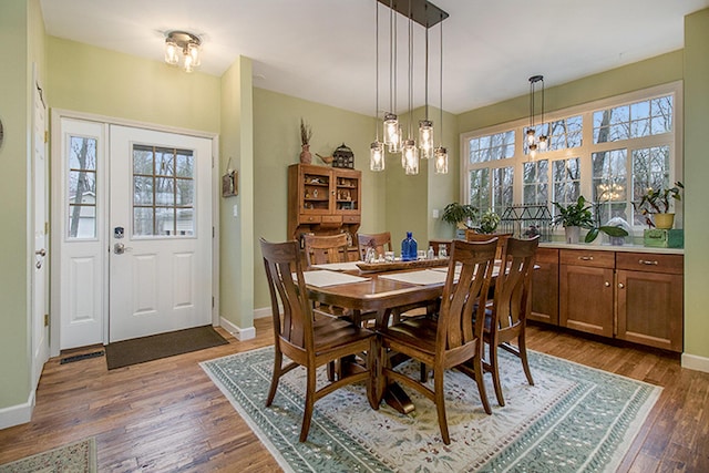 dining room featuring dark wood-style floors, plenty of natural light, and baseboards