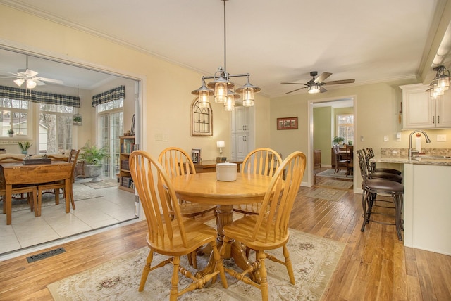 dining area with visible vents, crown molding, light wood finished floors, and ceiling fan