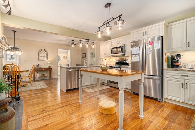 kitchen featuring stainless steel appliances, hanging light fixtures, and white cabinetry