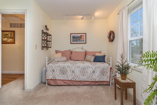 bedroom featuring track lighting, light colored carpet, visible vents, and baseboards