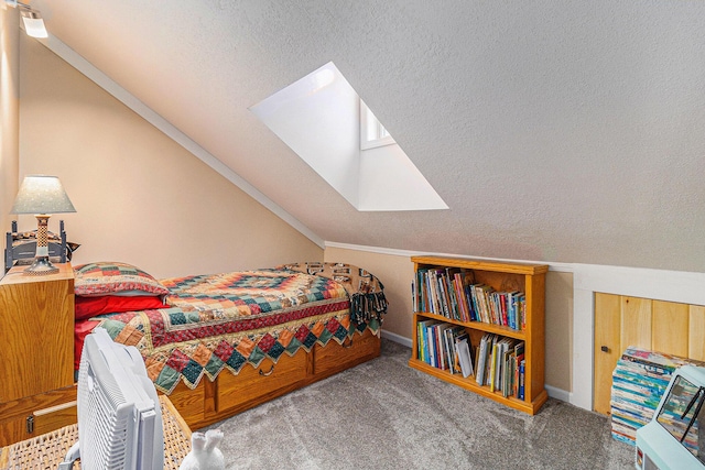 bedroom with lofted ceiling with skylight, carpet floors, and a textured ceiling