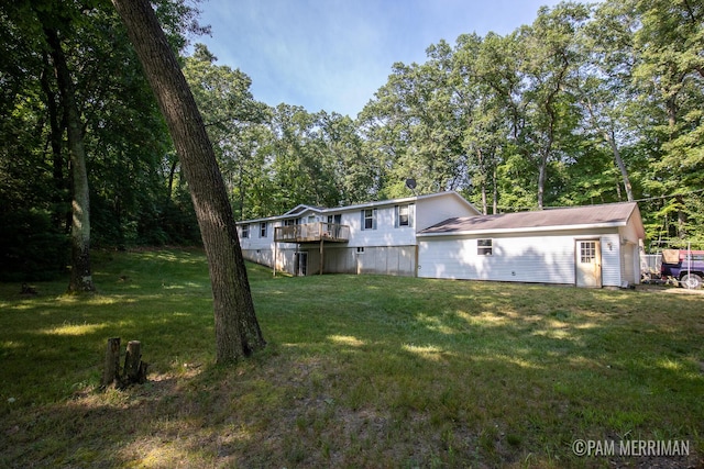 rear view of house featuring a wooden deck and a yard