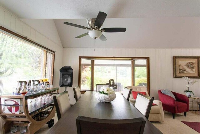 carpeted dining room with ceiling fan, lofted ceiling, and plenty of natural light