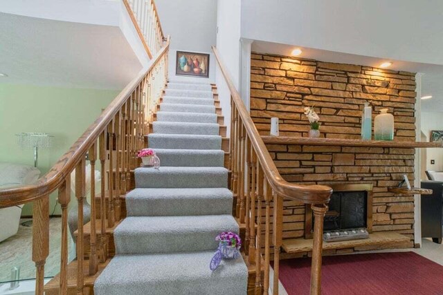 stairs featuring a stone fireplace