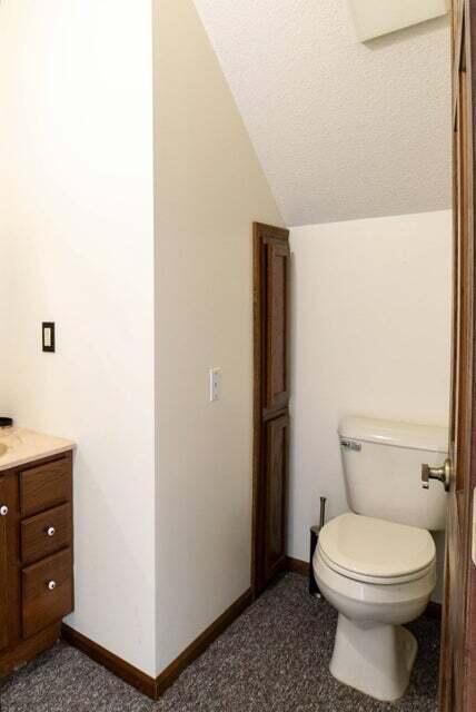 bathroom with a textured ceiling, vanity, vaulted ceiling, and toilet