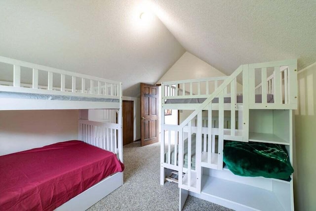 carpeted bedroom with a textured ceiling and vaulted ceiling