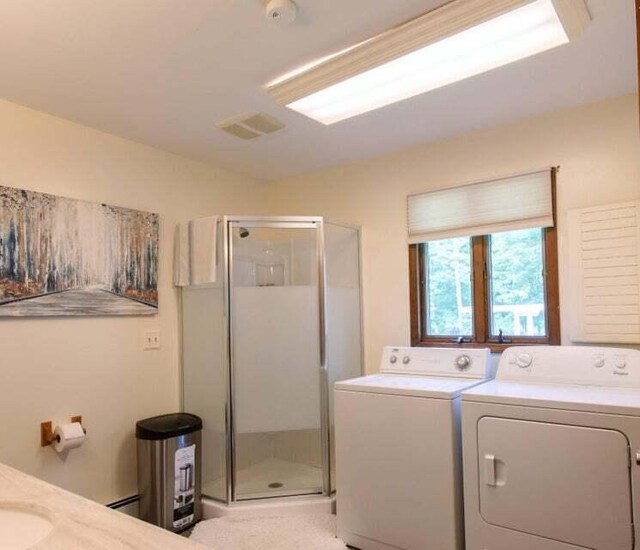 clothes washing area featuring independent washer and dryer and a baseboard radiator