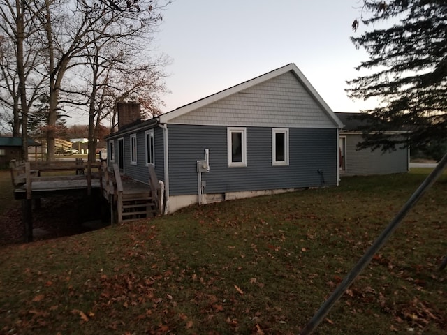 property exterior at dusk with a deck and a lawn