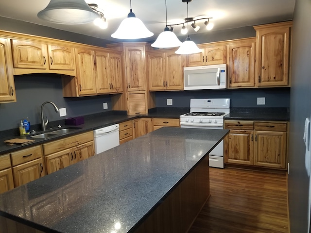 kitchen with sink, white appliances, hanging light fixtures, dark hardwood / wood-style floors, and dark stone counters